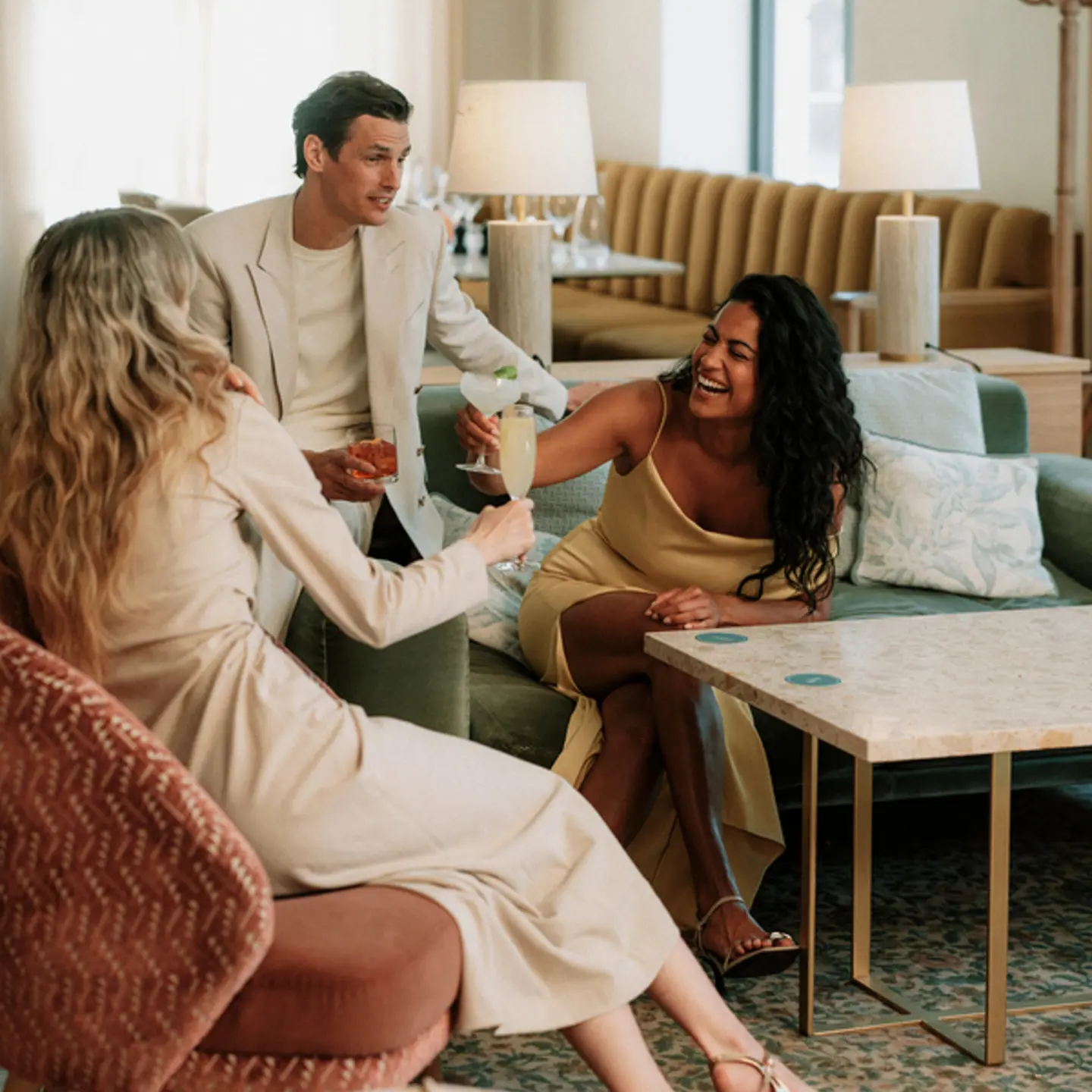 Tre personer som njuter av drinkar och socialiserar i en elegant lounge.