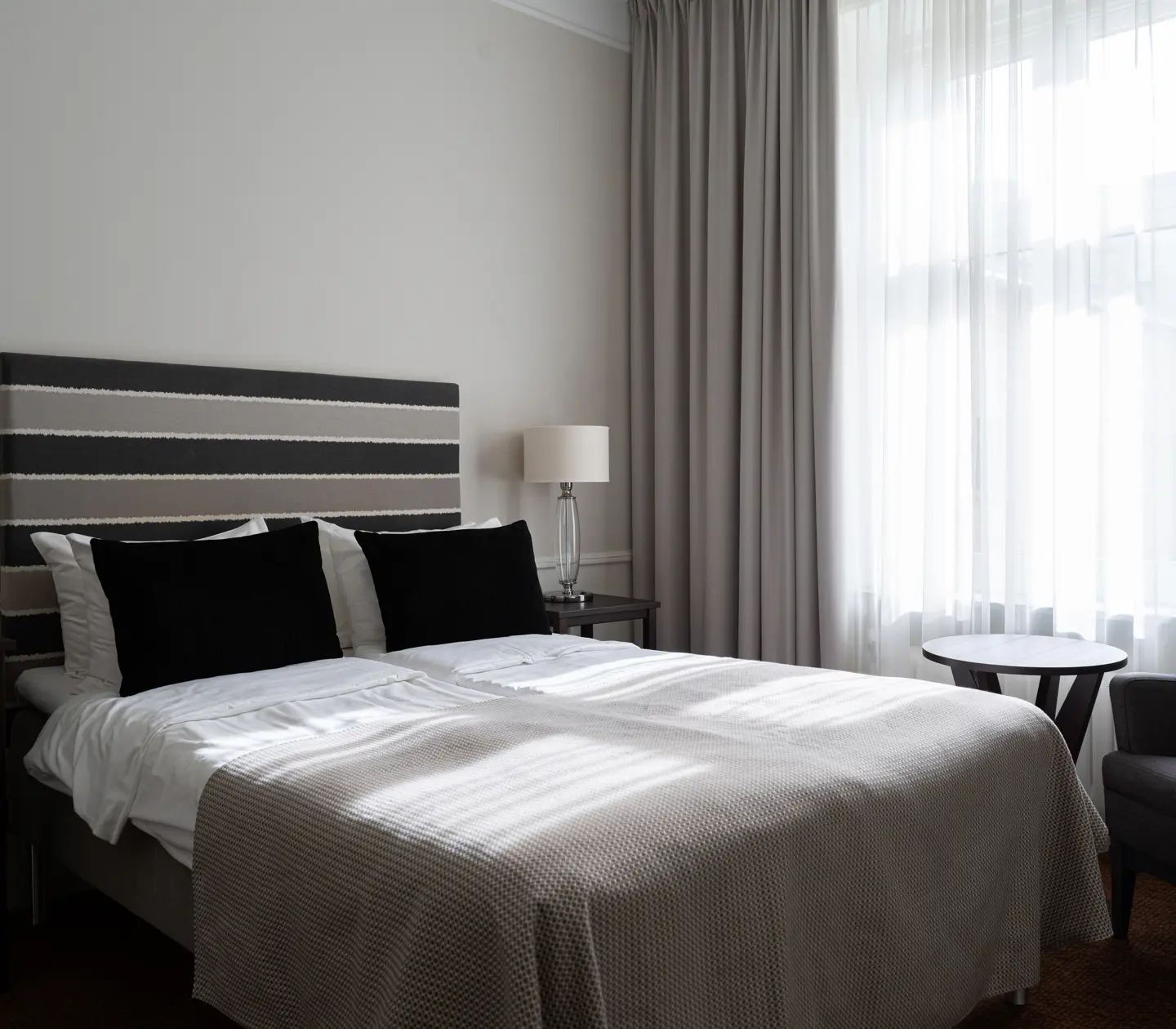 Hotellrum med dubbelsäng, fåtölj och fönster