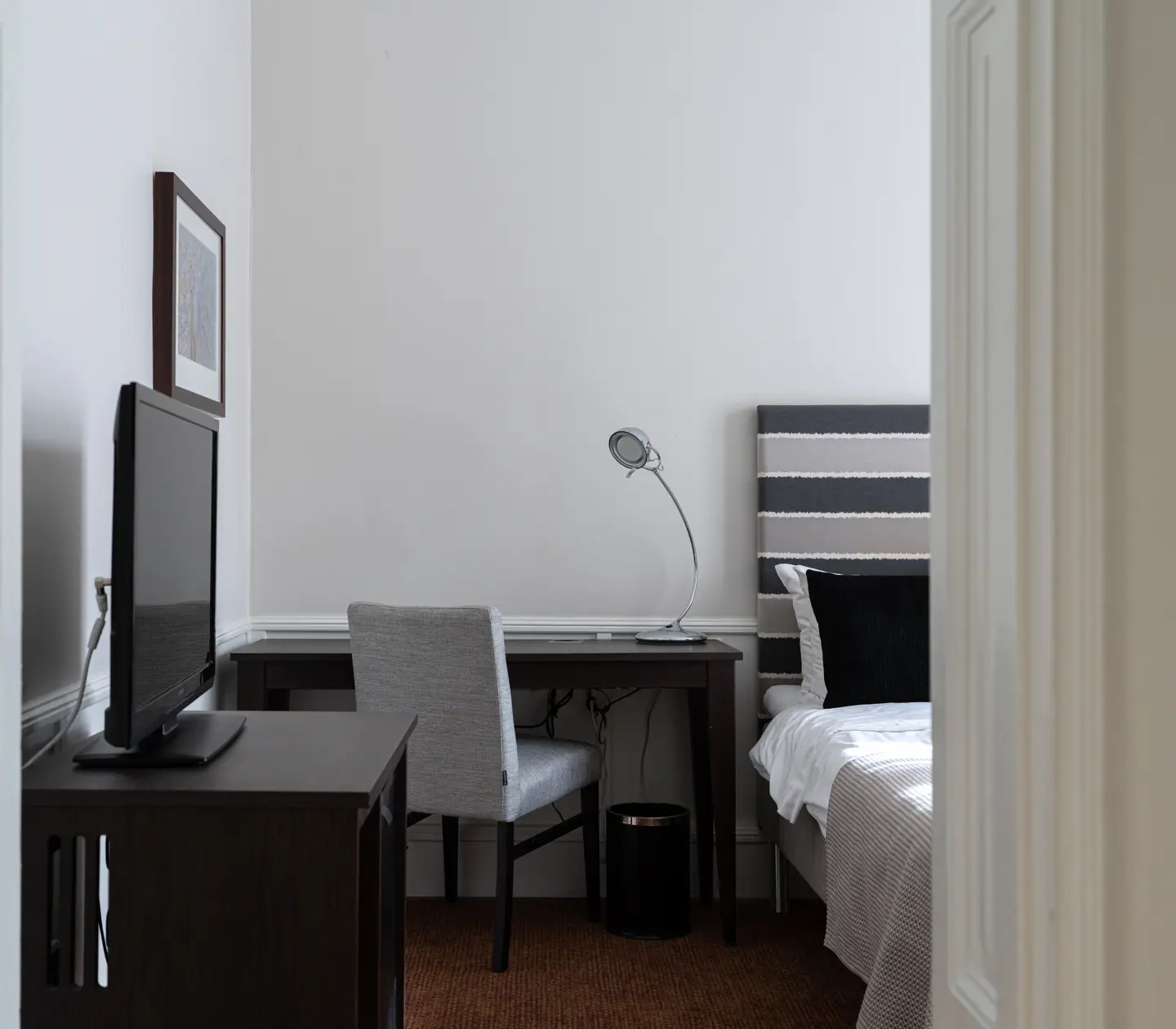 Hotellrum med del av säng, fåtölj, garderob och fönster