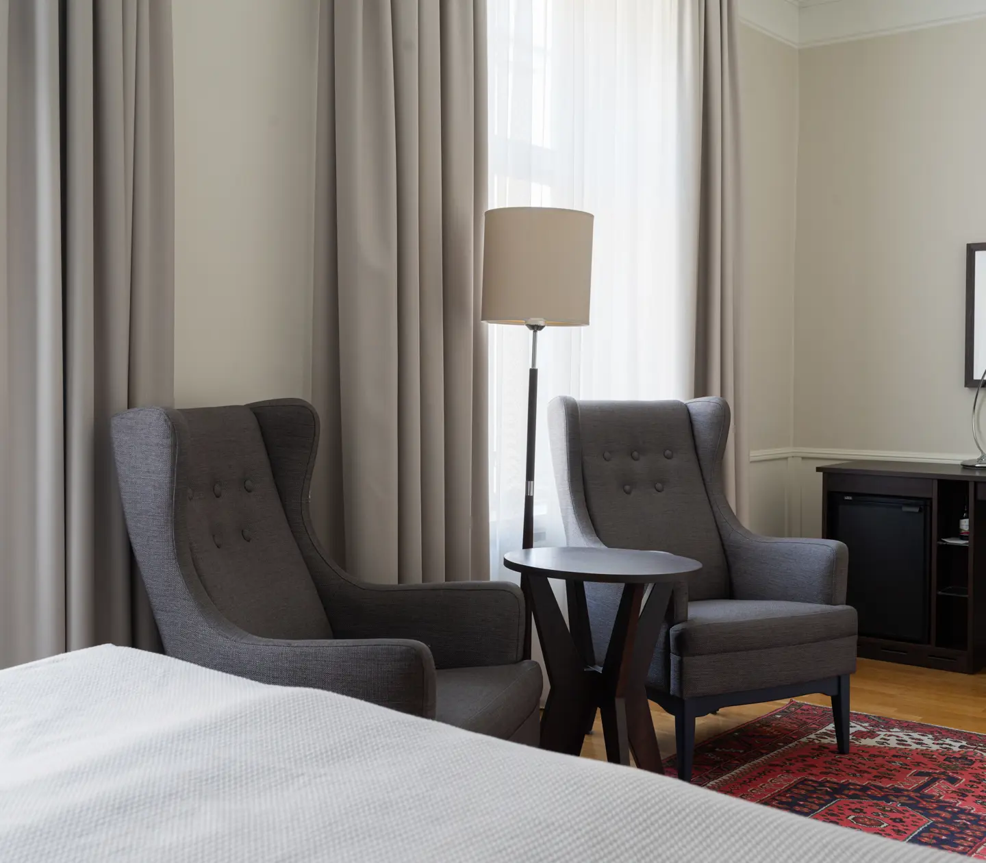 Hotellrum med dubbelsäng, fåtölj och fönster