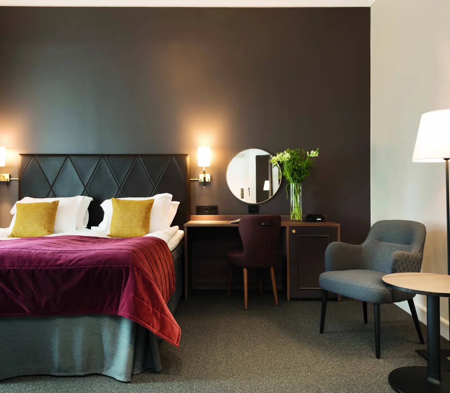 Ljust hotellrum med dubbelsäng, fåtölj och fönster