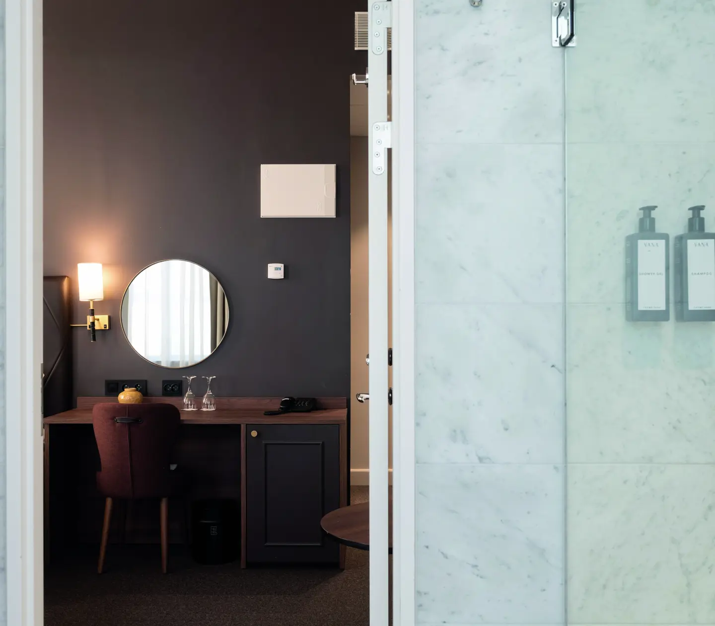 Mysigt hotellrum med blommig tapet, hörnsoffa och stora fönster