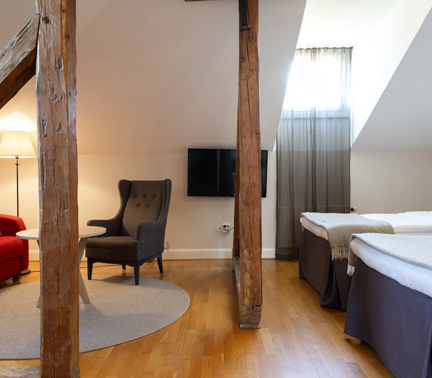 Ljust hotellrum med dubbelsäng, fåtöljer och fönster