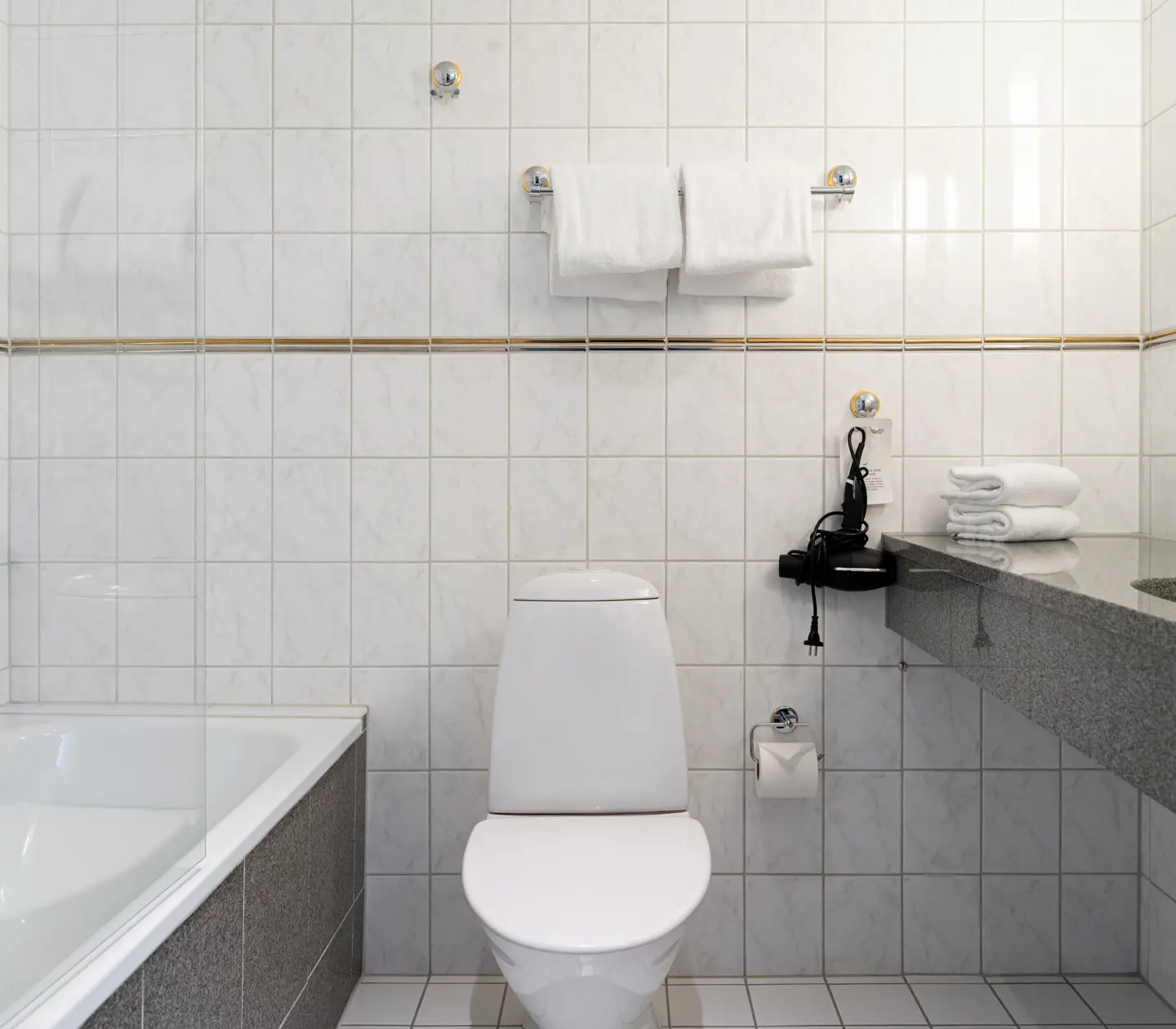 Ljust hotellrum med dubbelsäng, spegel och bukett