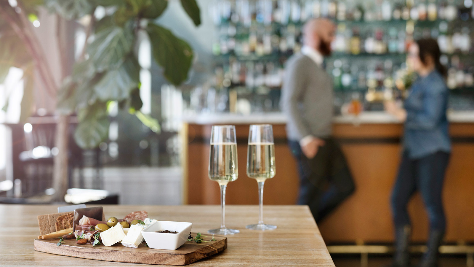 Charkbricka med Champagneglas på bord och två personer i bakgrunden