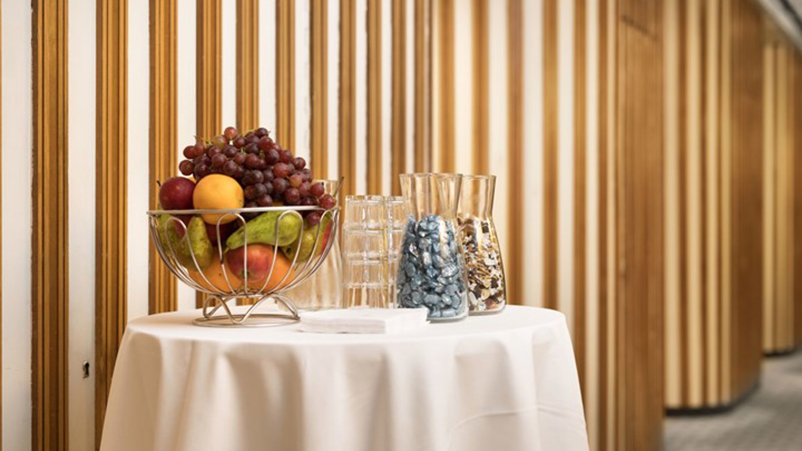 Detaljbild på bord med vit duk, fruktskål, glas och godis