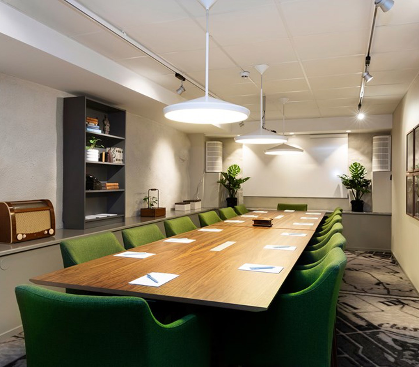 Konferensrum med styrelsesittning, gröna stolar och brunt träbord