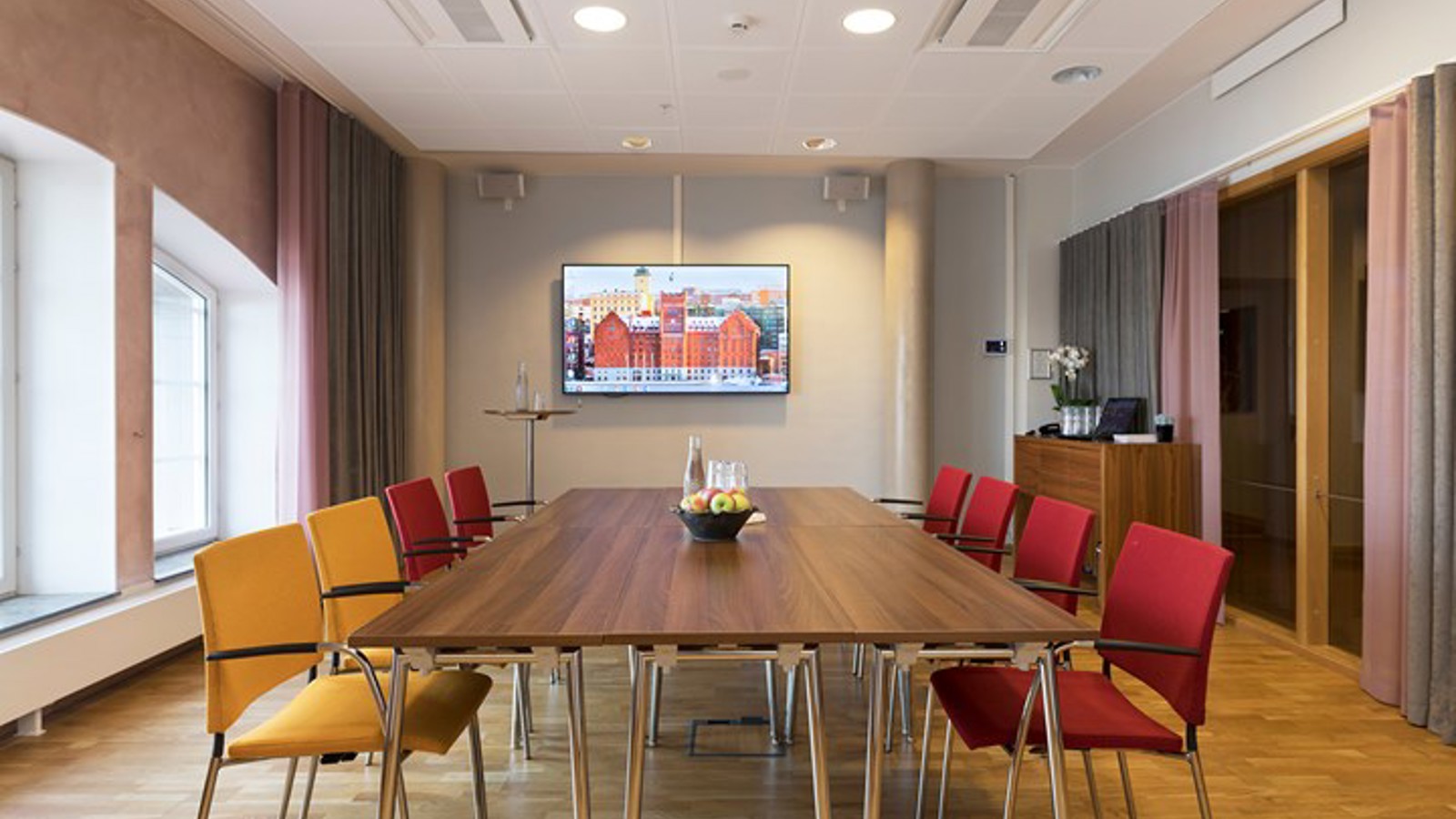 Board room with brown table, yellow and red chairs and large windows
