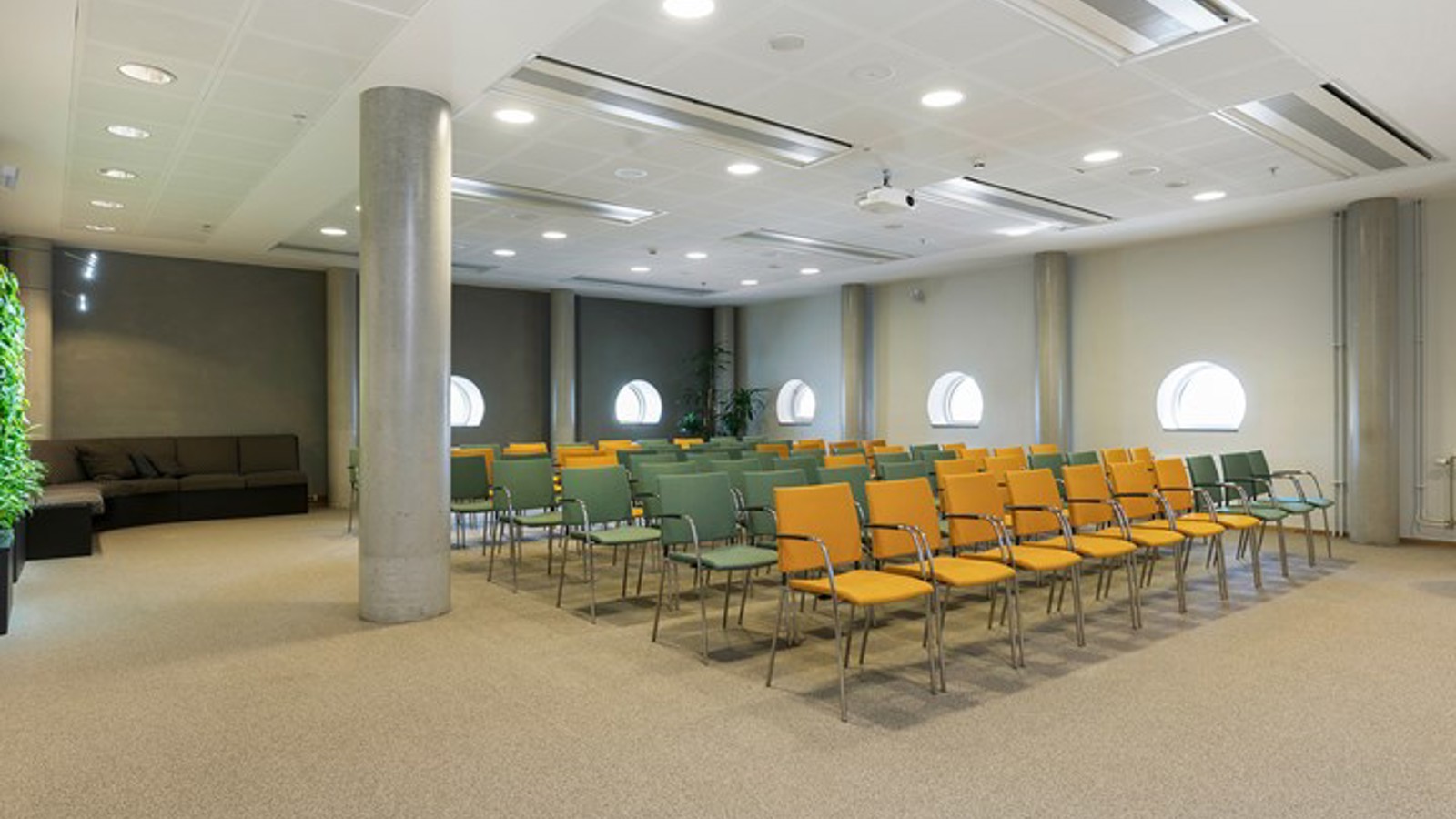 Konferensrum med biosittning, gula och blå stolar och halvmånefönster