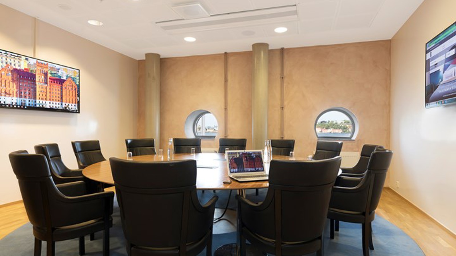Konferensrum med runt bord, svarta fåtöljer och små runda halvmånefönster