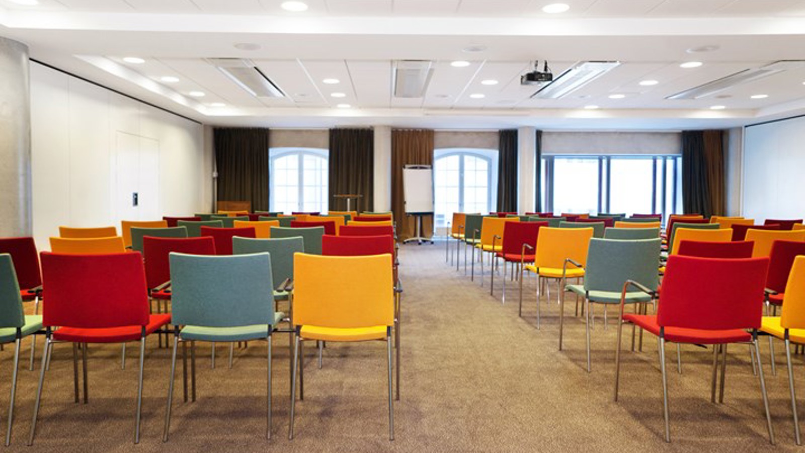 Konferensrum med färgglada stolar, vita väggar och stora fönster