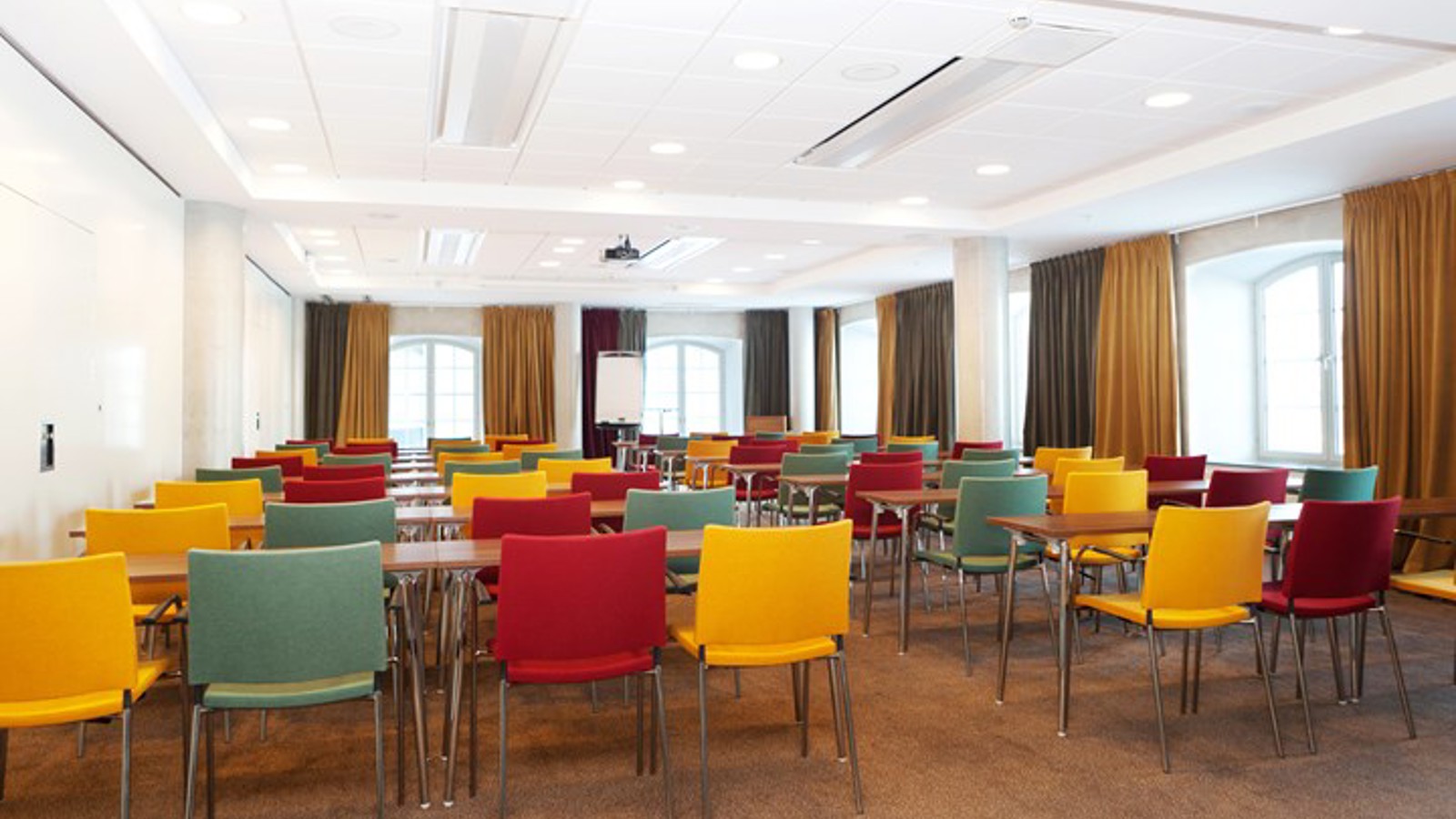 Konferensrum med skolsittning, färgglada stolar och stora fönster