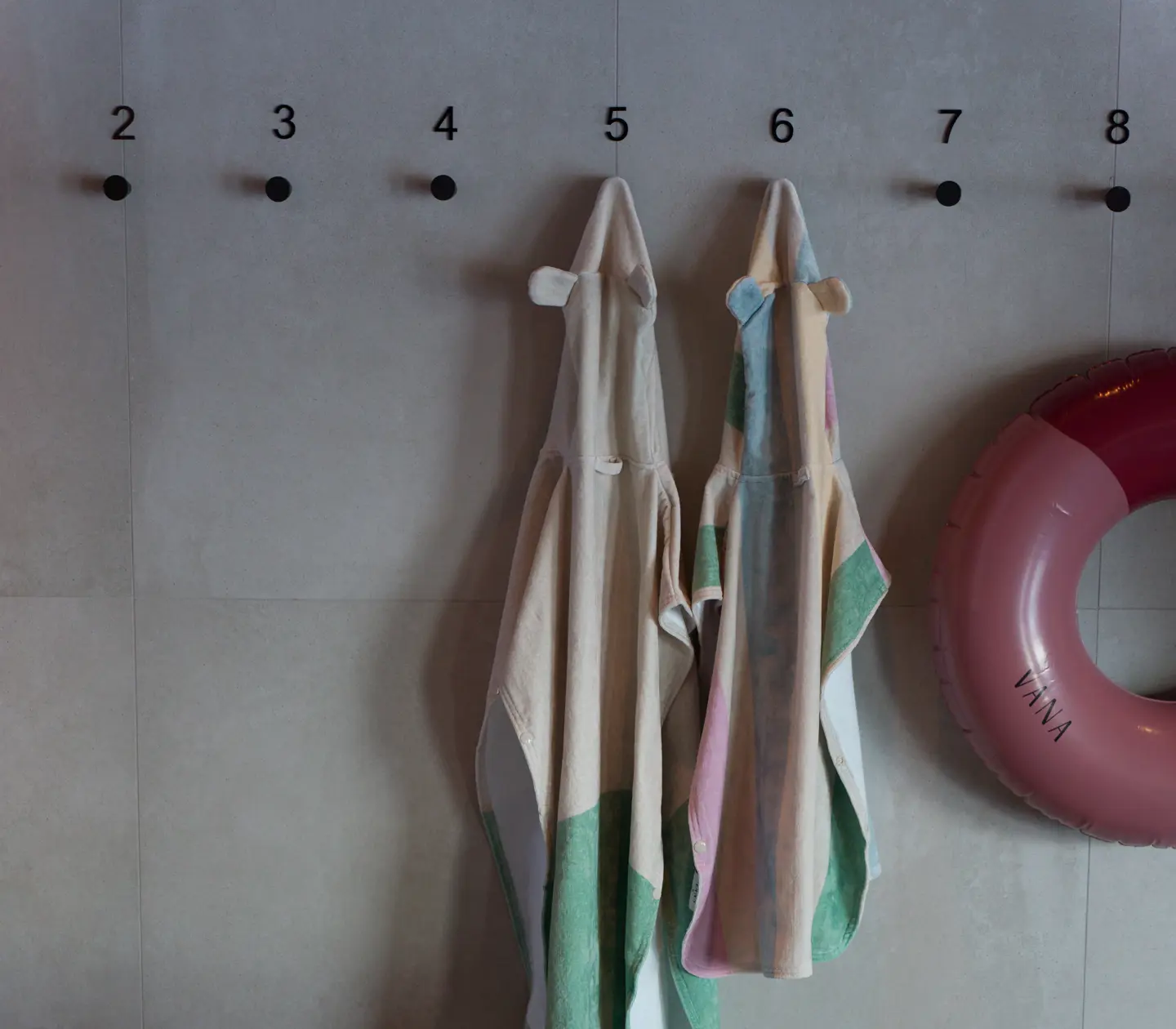 Handdukar hängande på krokar numrerade 2 till 8 med en rosa badring bredvid
