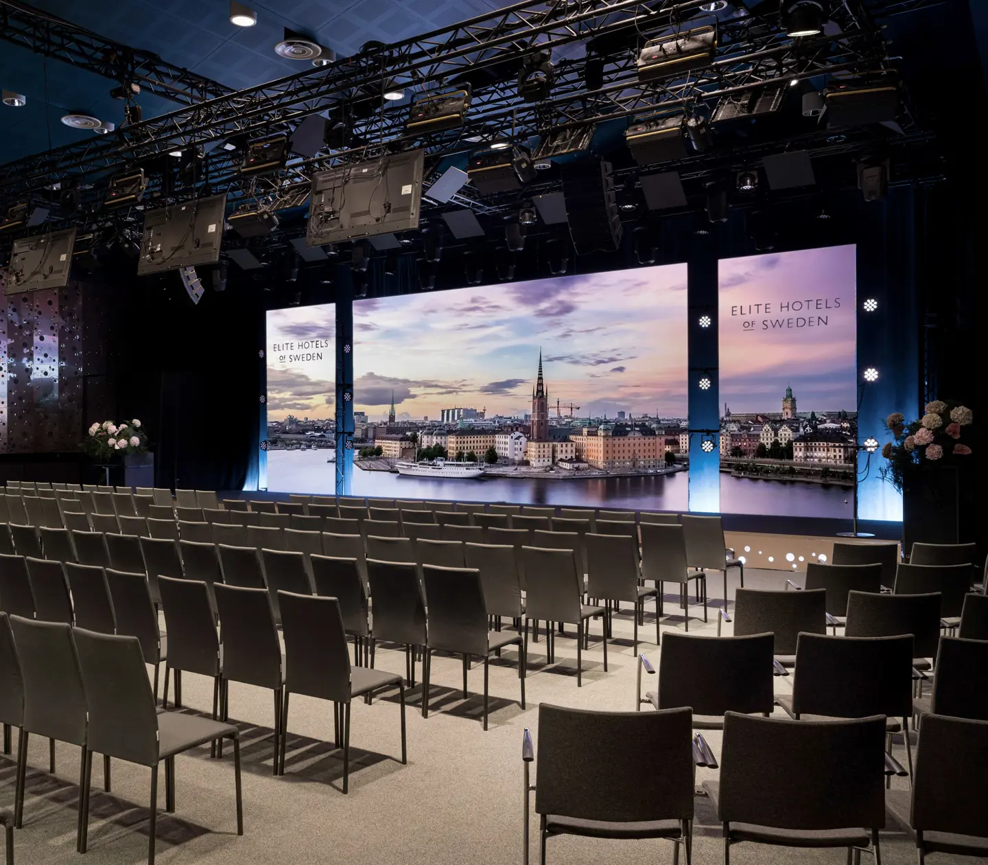 Konferenssal med ordnade gröna och orangea stolar inför scen med Hollywood-skylt tema.