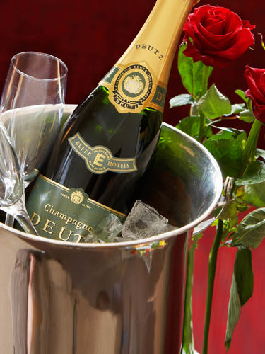 Champagne flaska med rosor och glas.