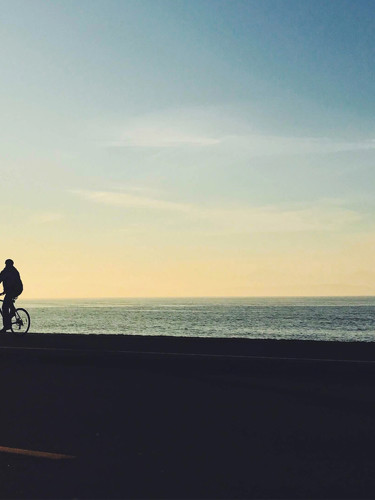 En person som cyklar längs havet i solnedgångsljus