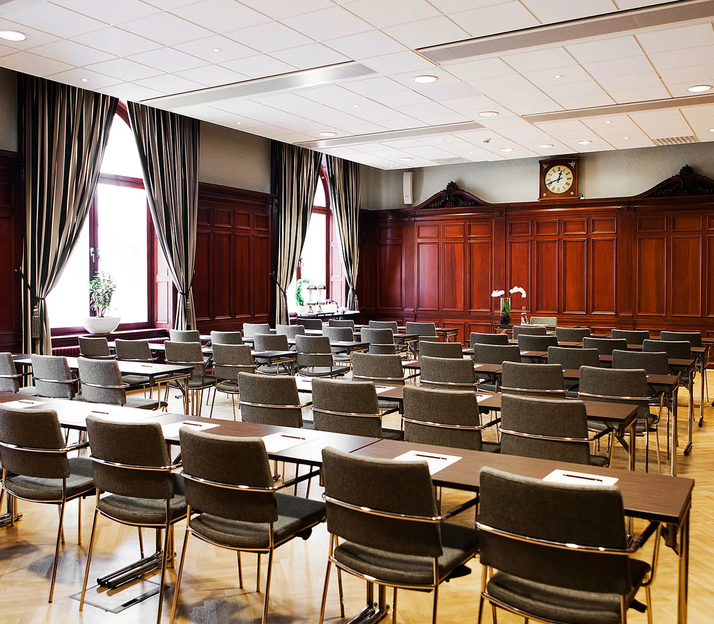 Röd konferenssal med många stolar, bord och fönster