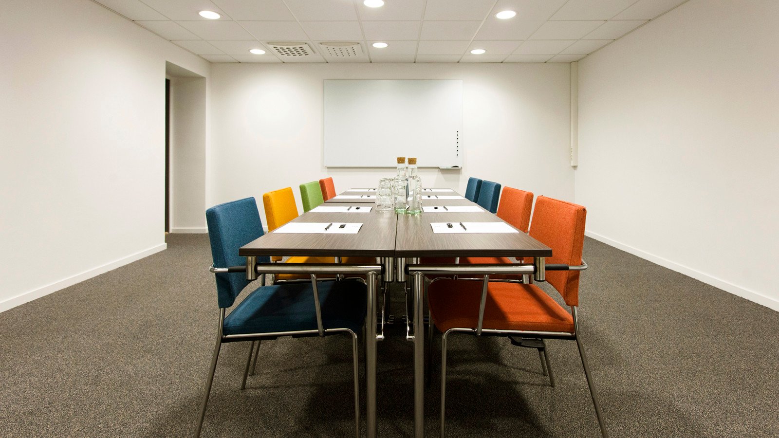 White conference room with table and colourful chairs