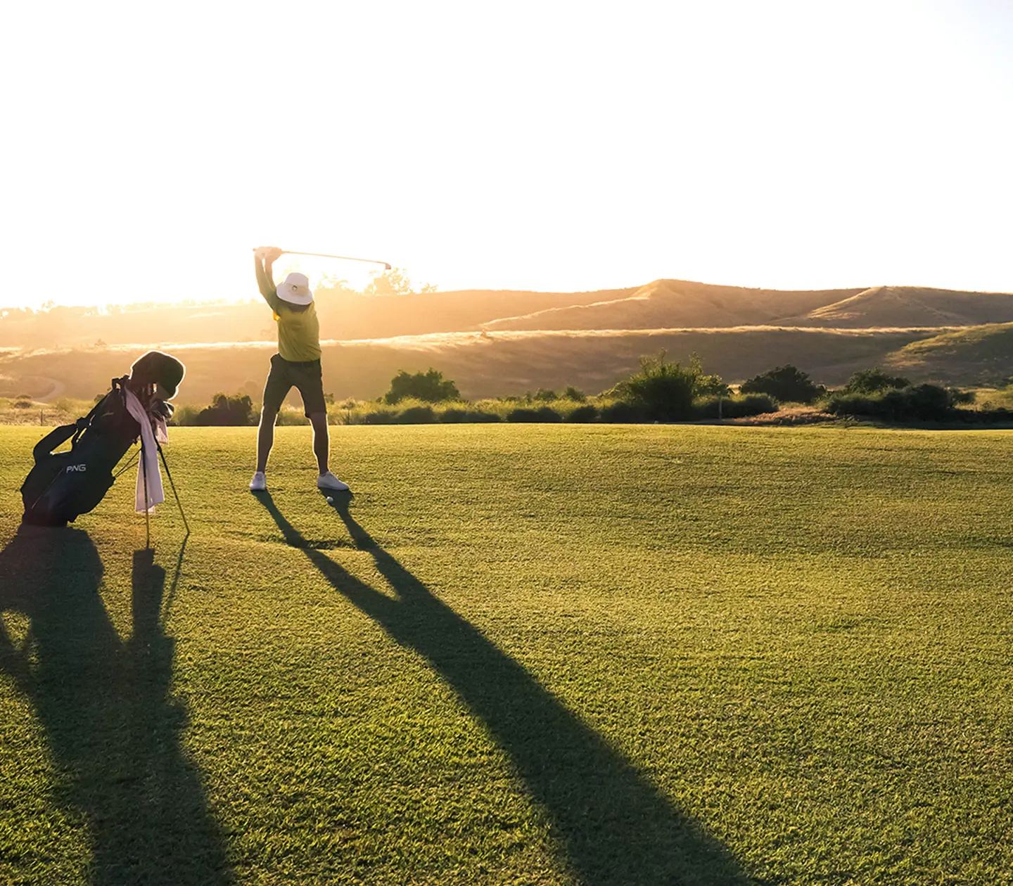 Kvinna i golfkläder lyfter upp en klubba ur en bag
