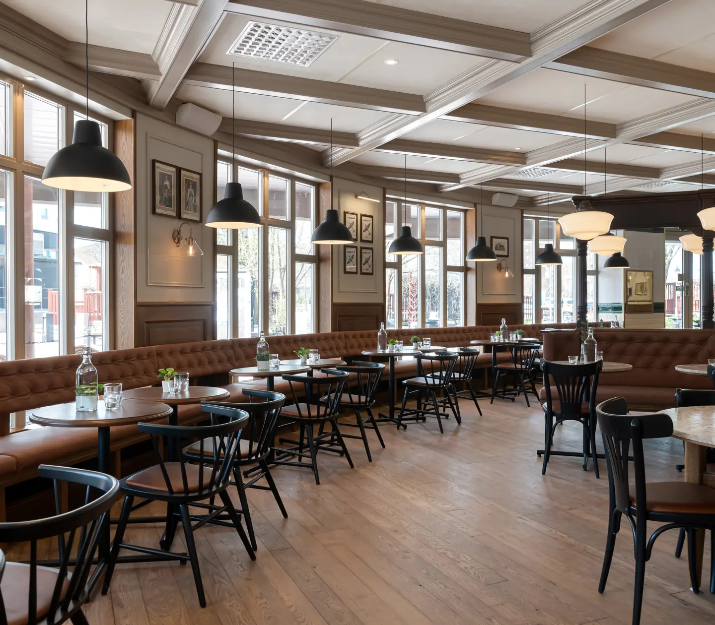 Restaurant environment with tables, ceiling lights and large windows
