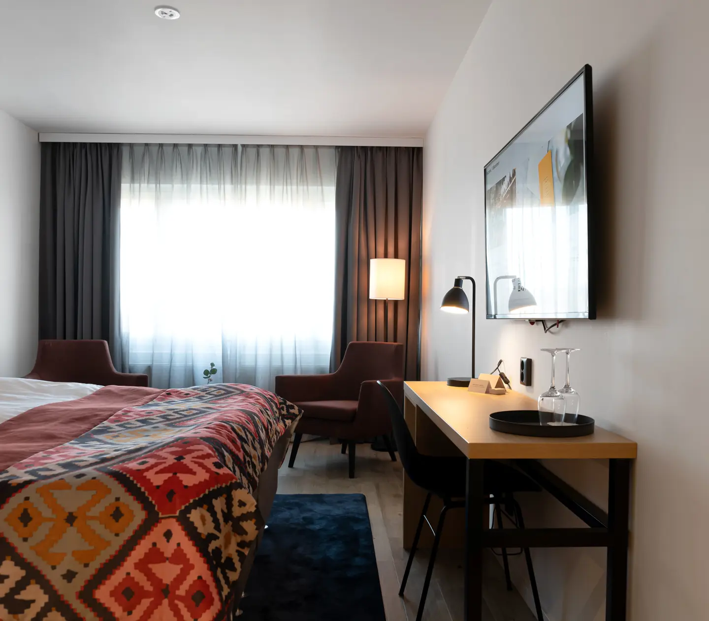 Cozy hotel room with double bed, armchairs and desk