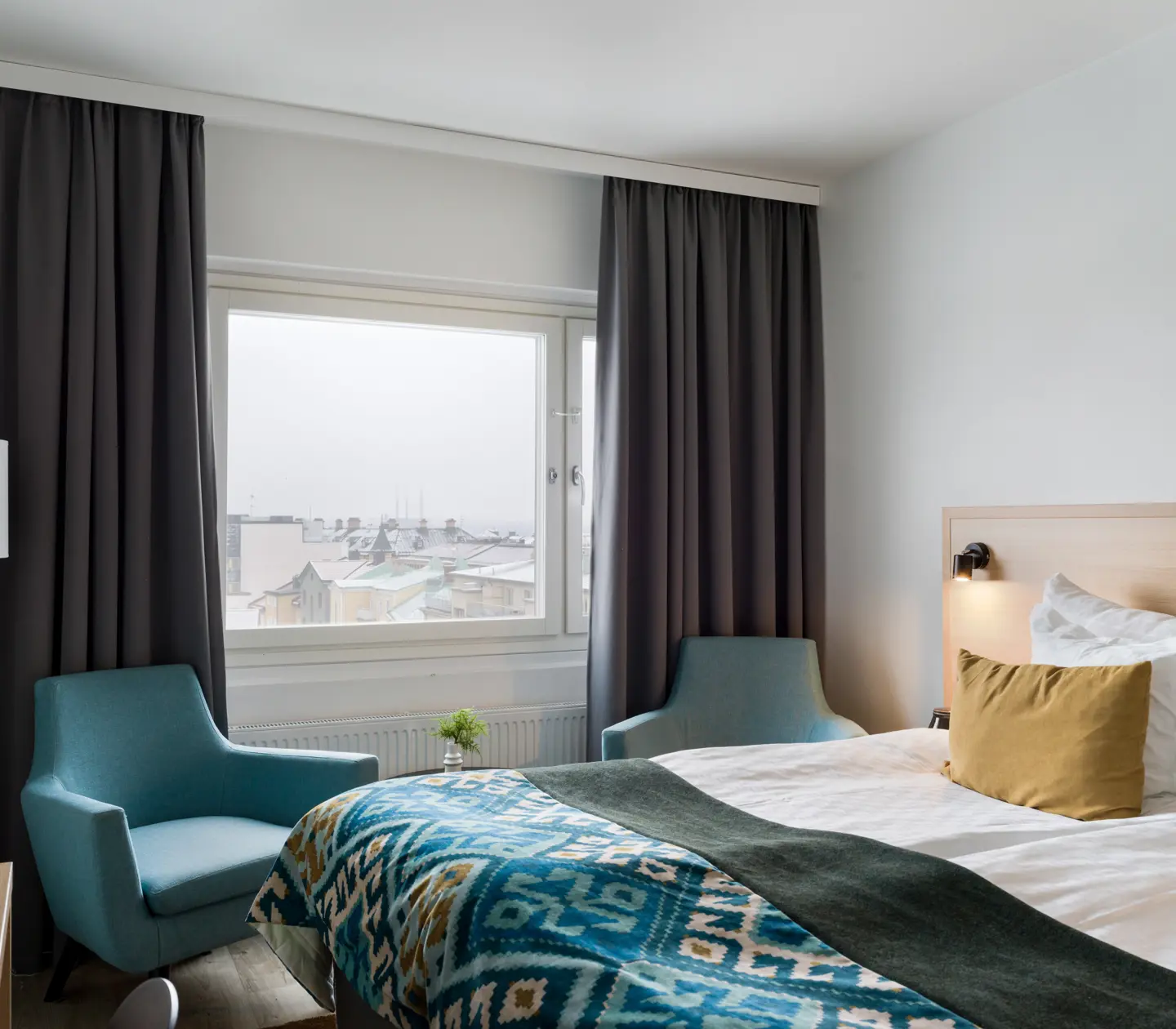 Bright hotel room with double bed, armchairs and window
