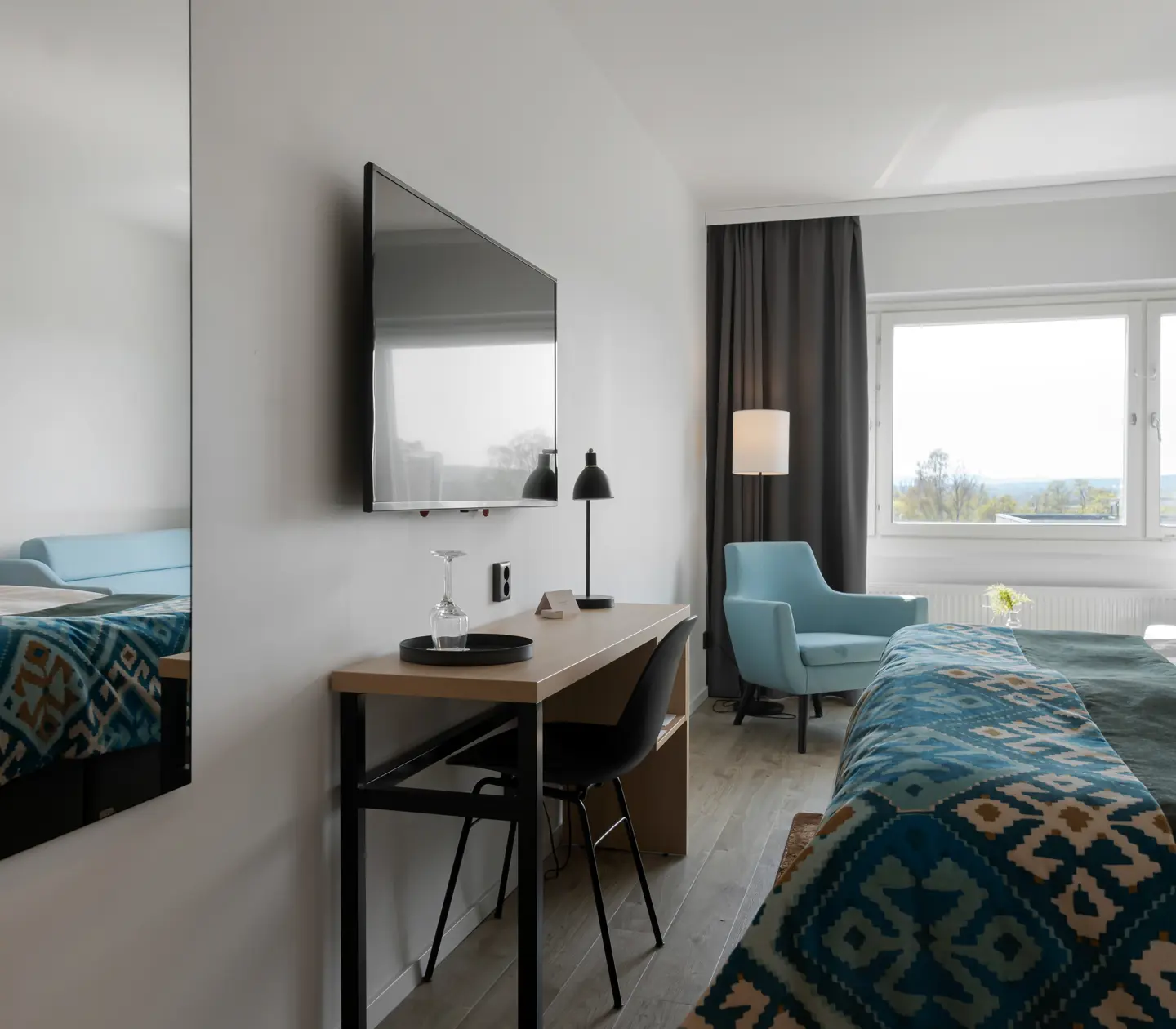 Hotel room with double bed, desk and armchairs