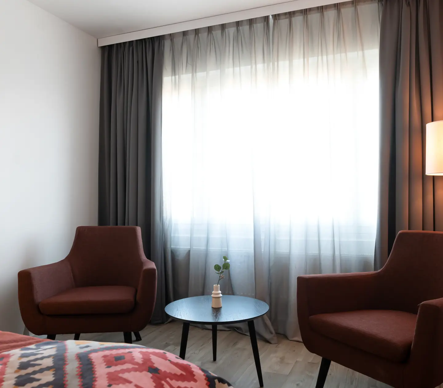 Armchairs, small table and curtains in front of window