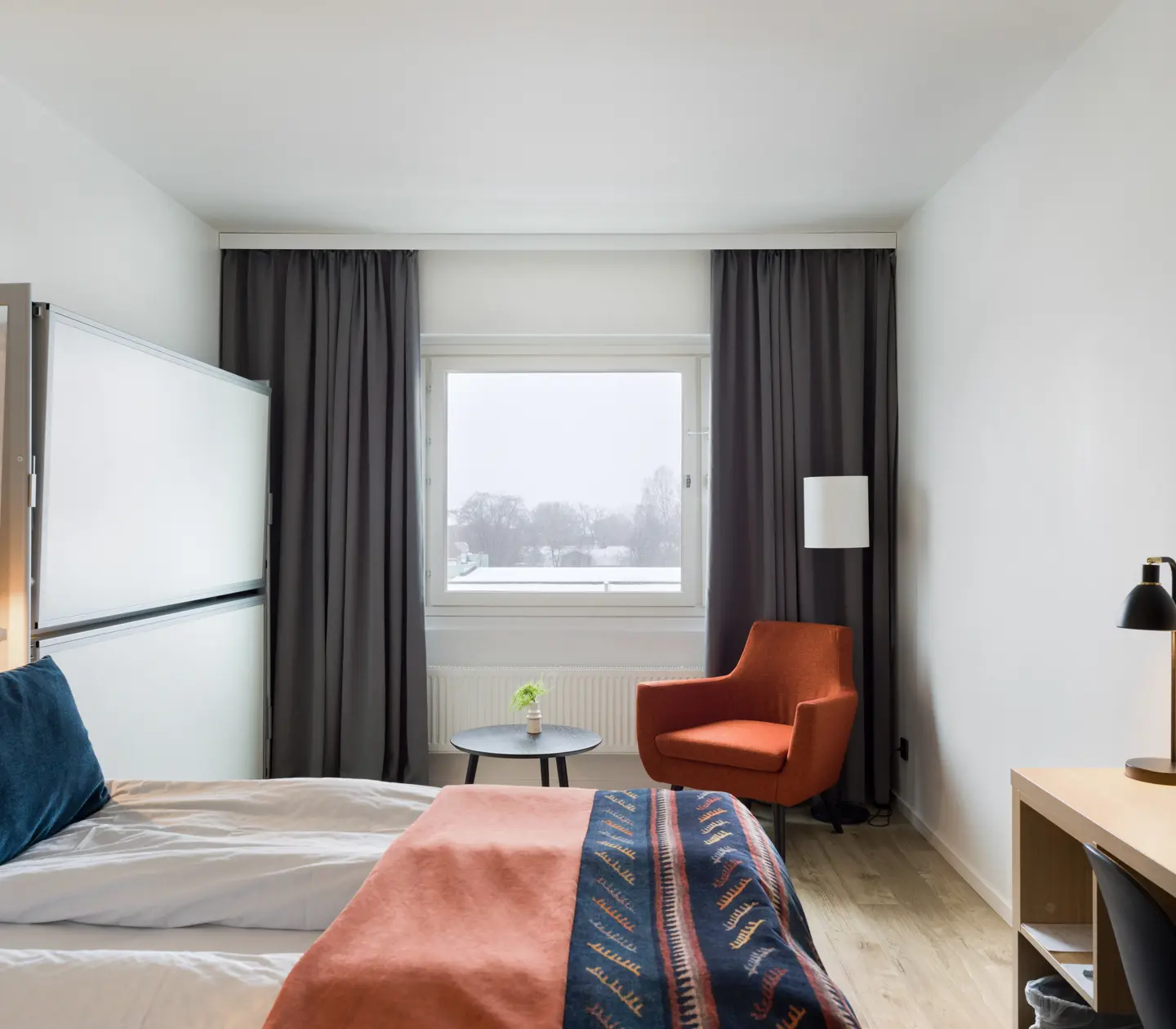 Hotel room with double bed, fold-up bunk bed and armchair