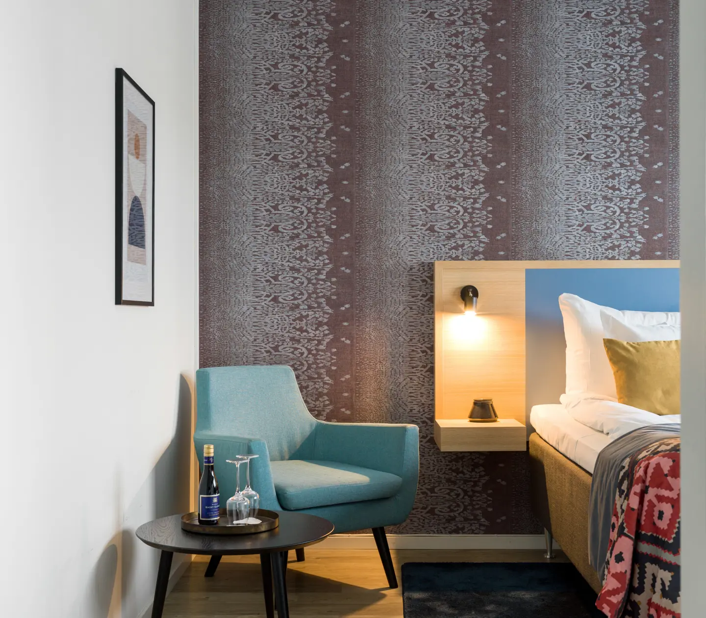 Hotel room with wallpaper, part of bed and armchair