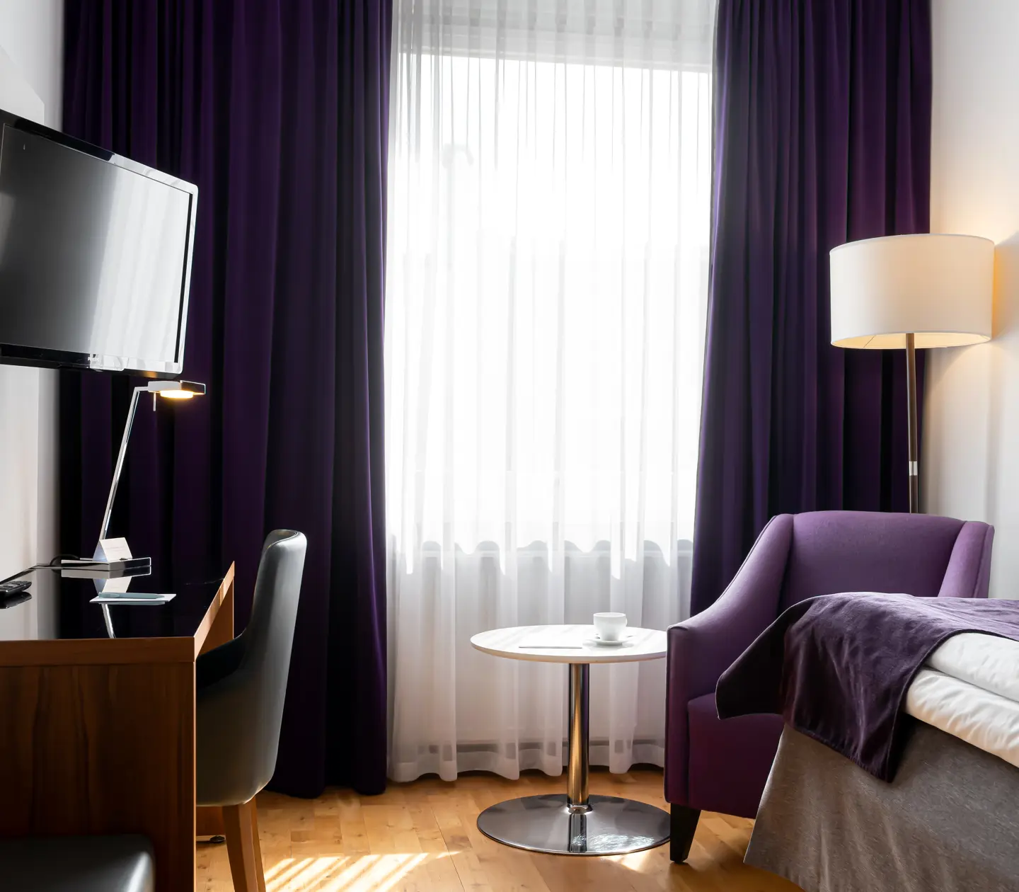 Hotel room with single bed, desk and armchair