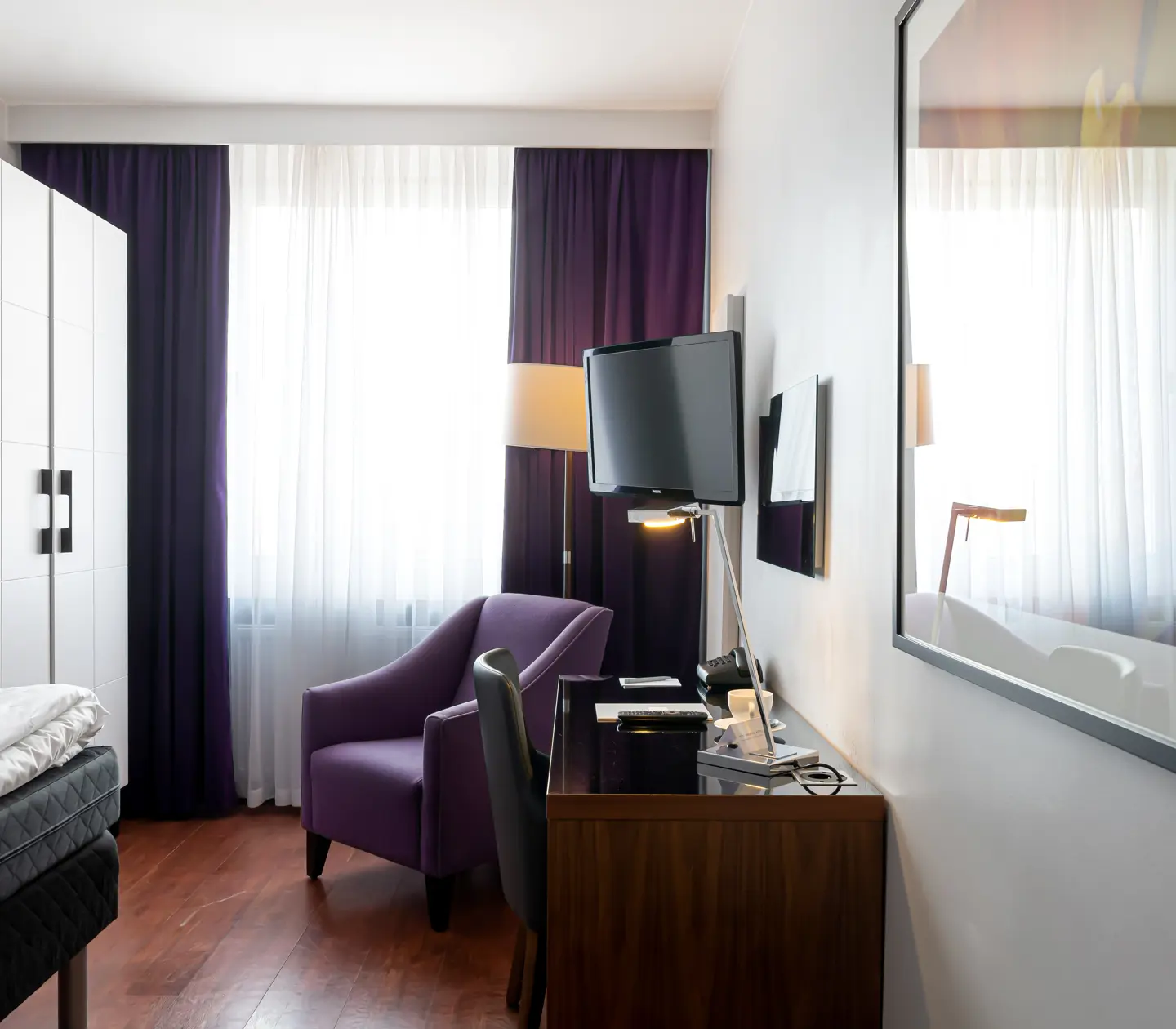 Hotel room with desk, armchair and wardrobe