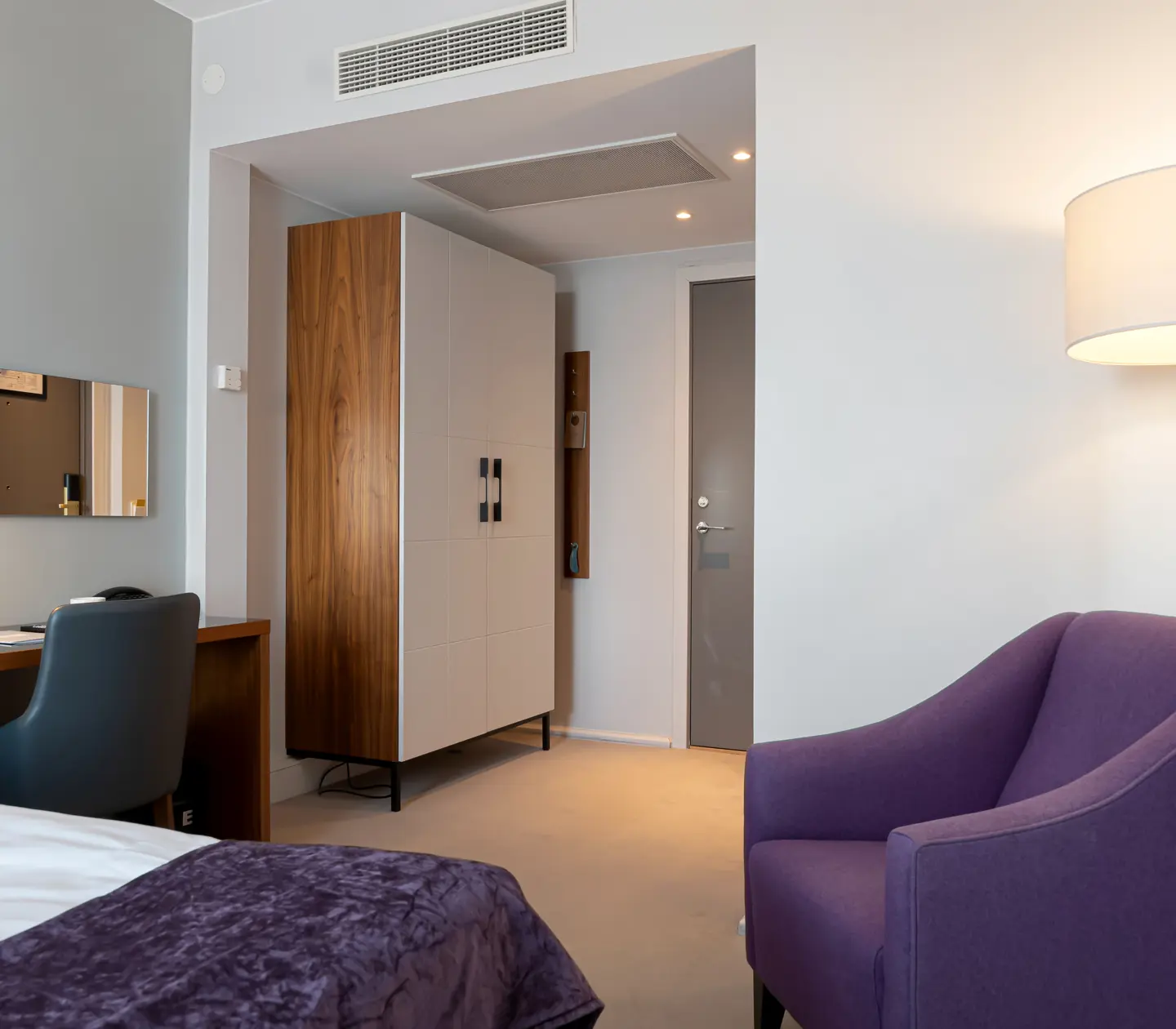 Hotel room with armchair, desk and wardrobe