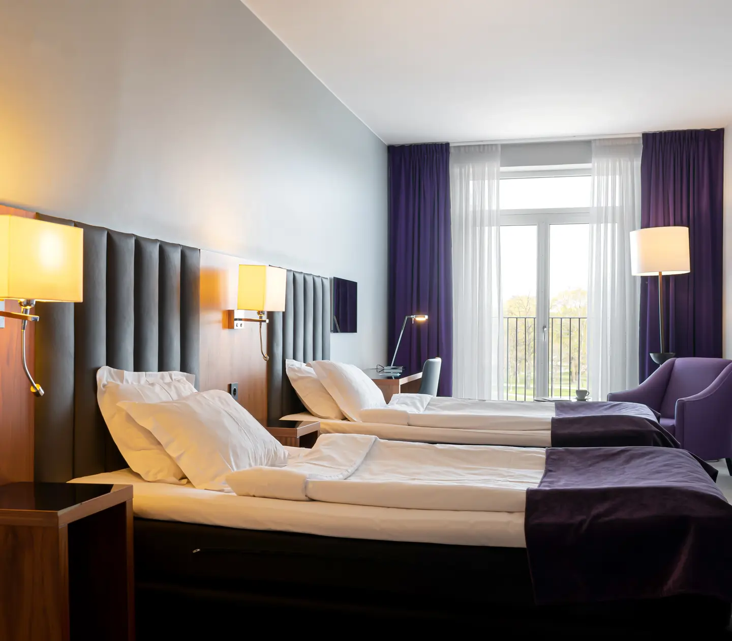 Hotel room with two single beds, armchair and desk