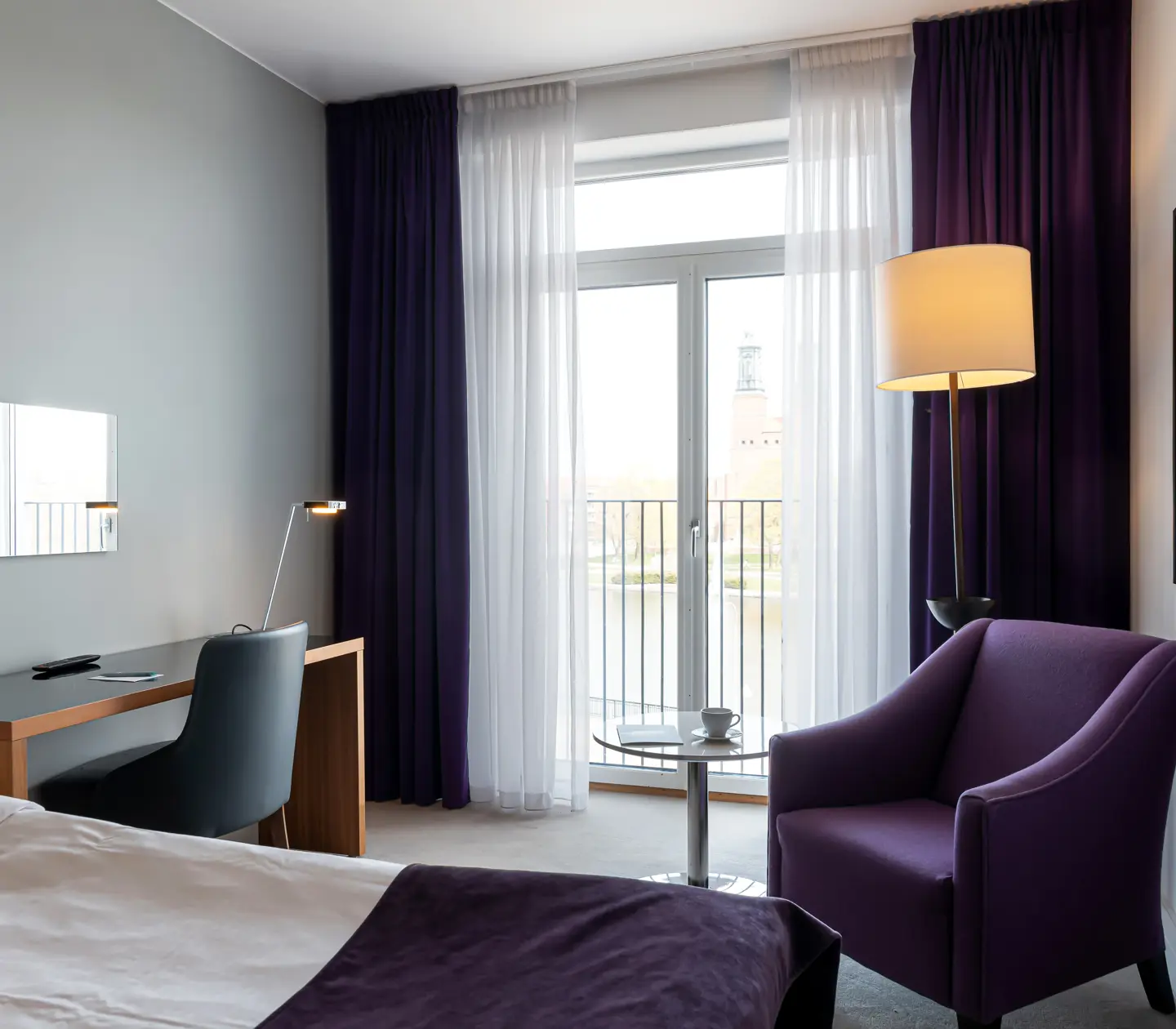 Hotel room with armchair, desk and large window