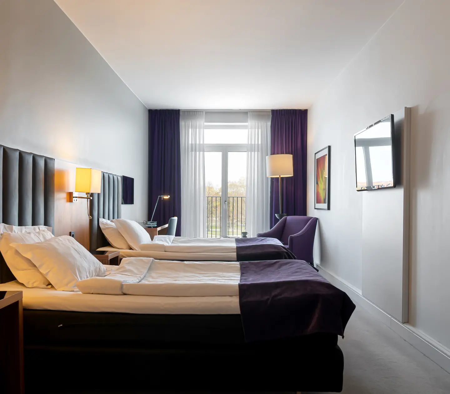 Hotel room with two single beds, armchairs and TV