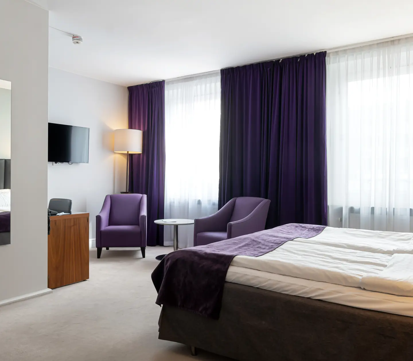 Hotel room with double bed, armchairs and mirror