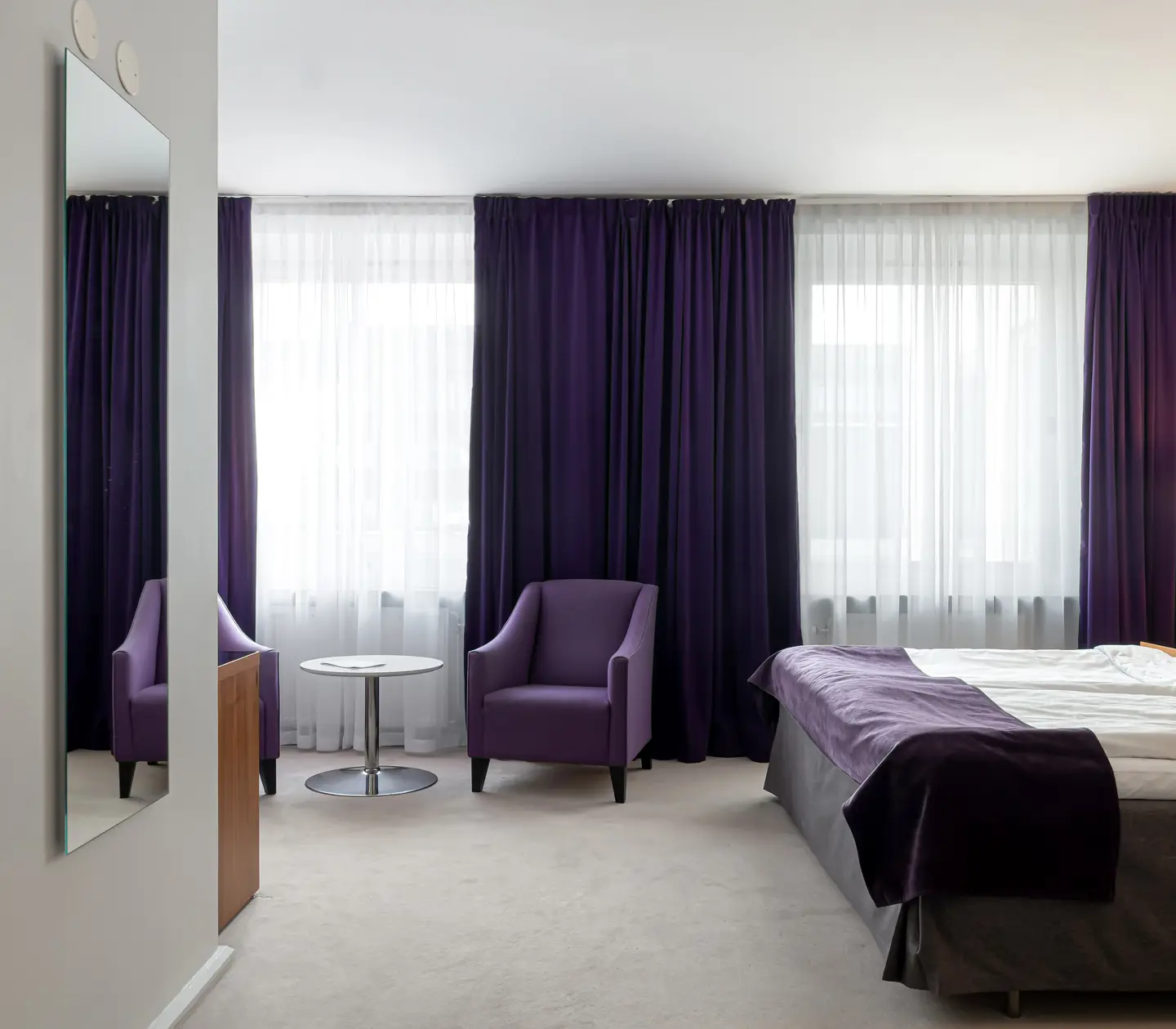 Hotel room with double bed, armchairs and mirror