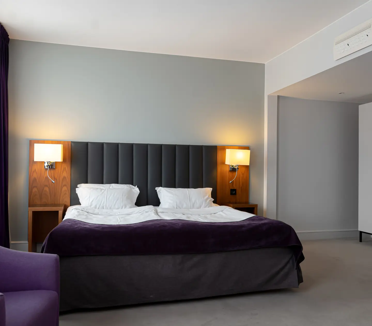 Hotel room with double bed, armchair and wardrobe