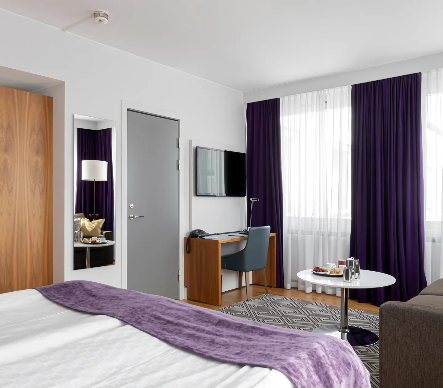 Hotel room with sofa, desk and mirror