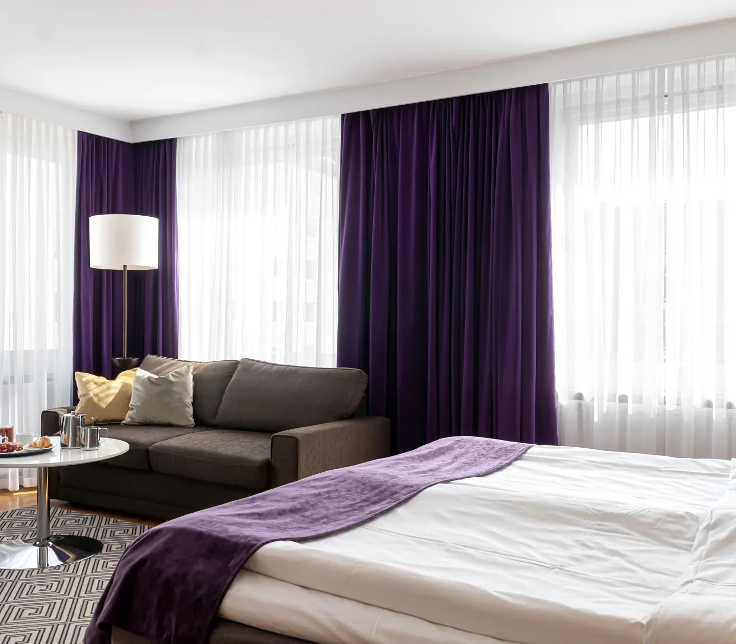 Hotel room with bed, sofa and large windows