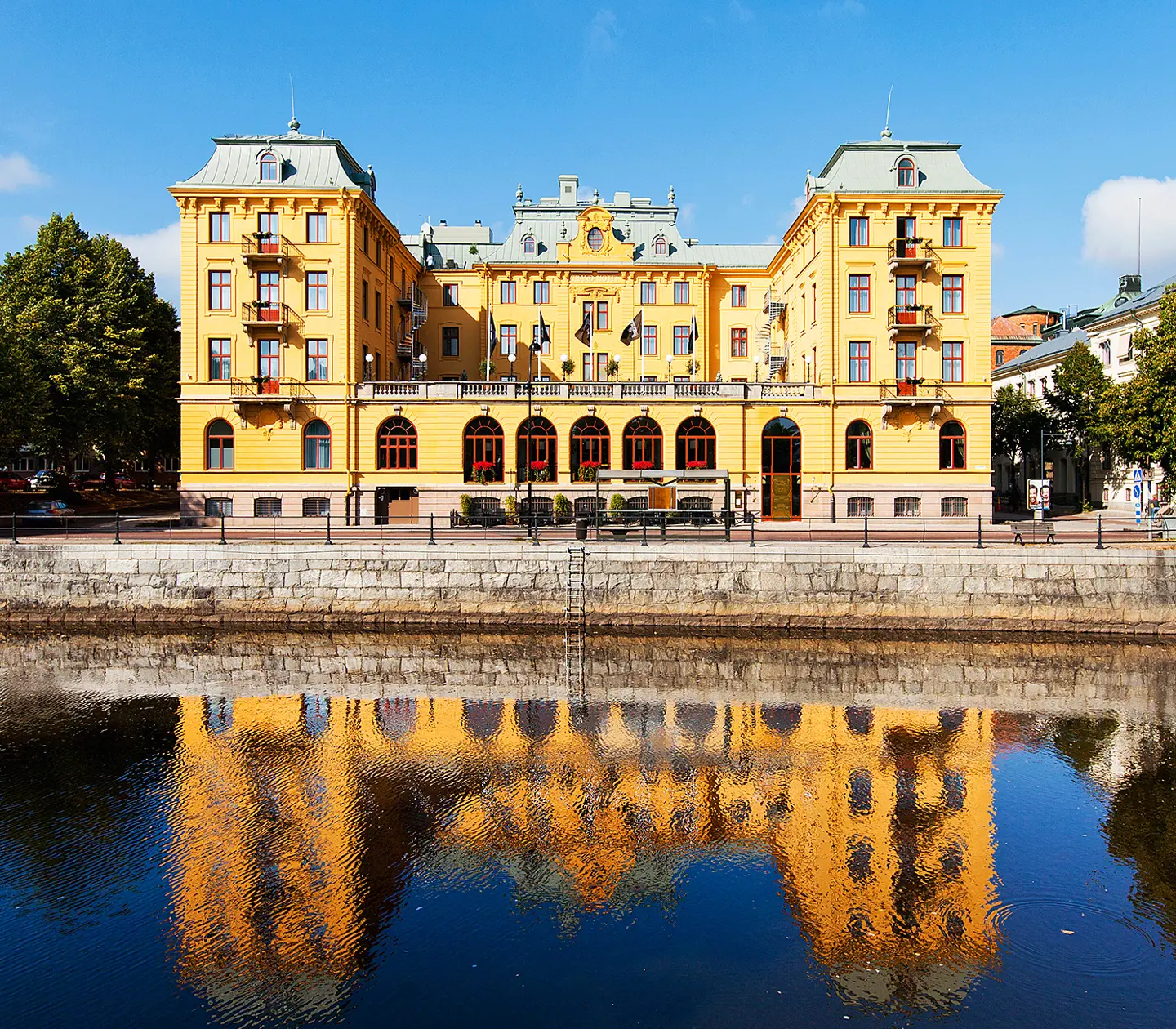 Gul byggnad med reflektion i vatten vid kaj i Sverige.