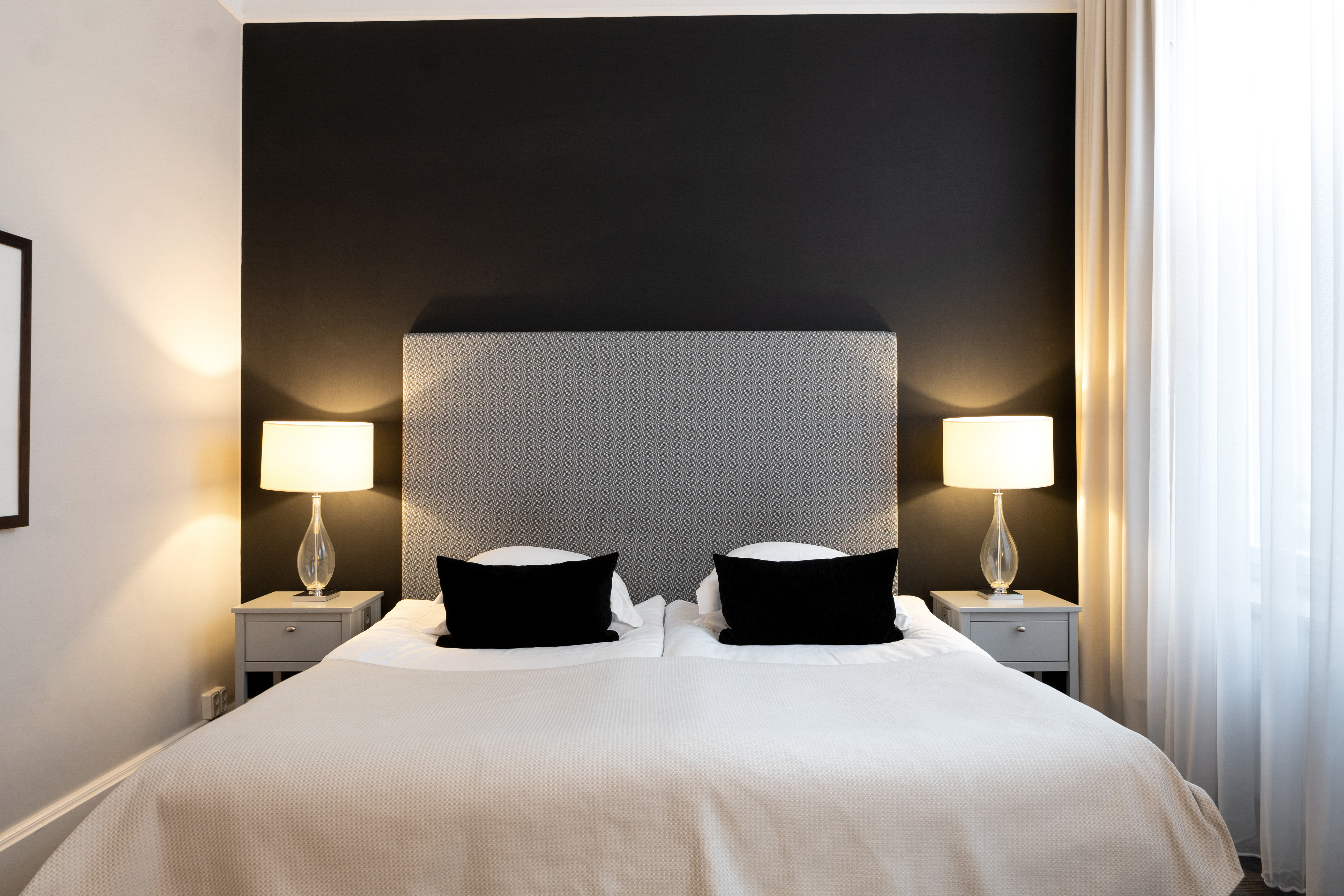 Hotellrum med svart vägg, säng och sänglampor