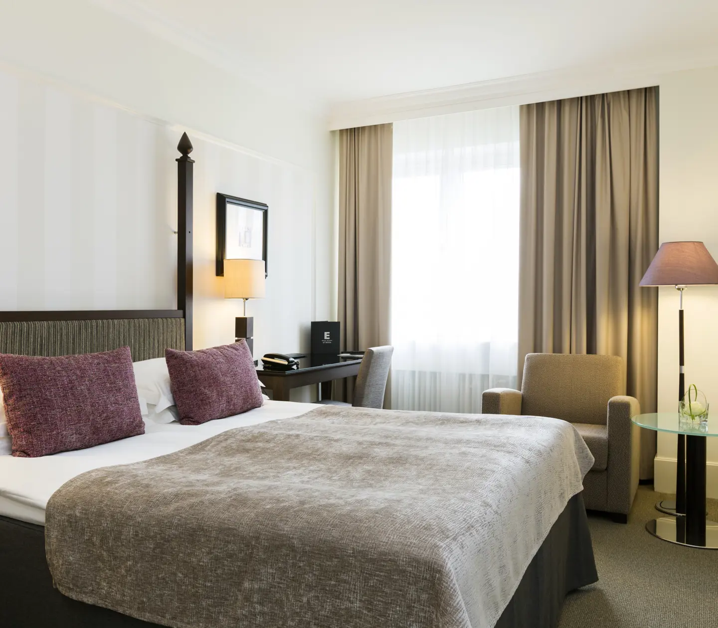 Cozy hotel room with double bed, desk and armchair