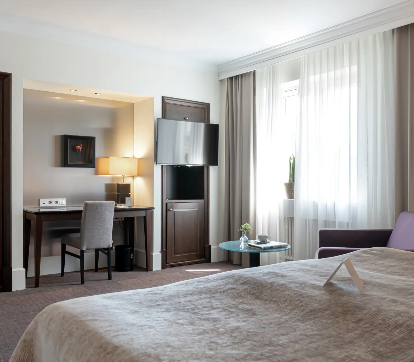 Hotel room with armchair, desk and TV