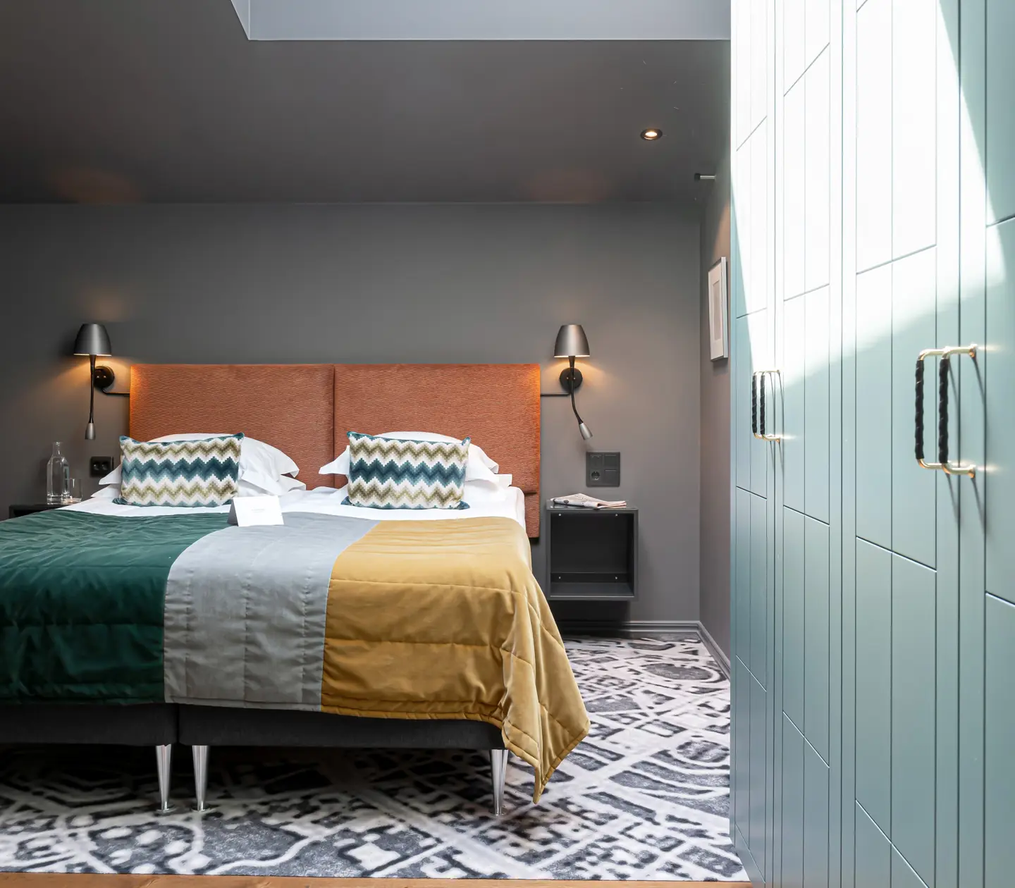 Colorful hotel room with double bed and wardrobes