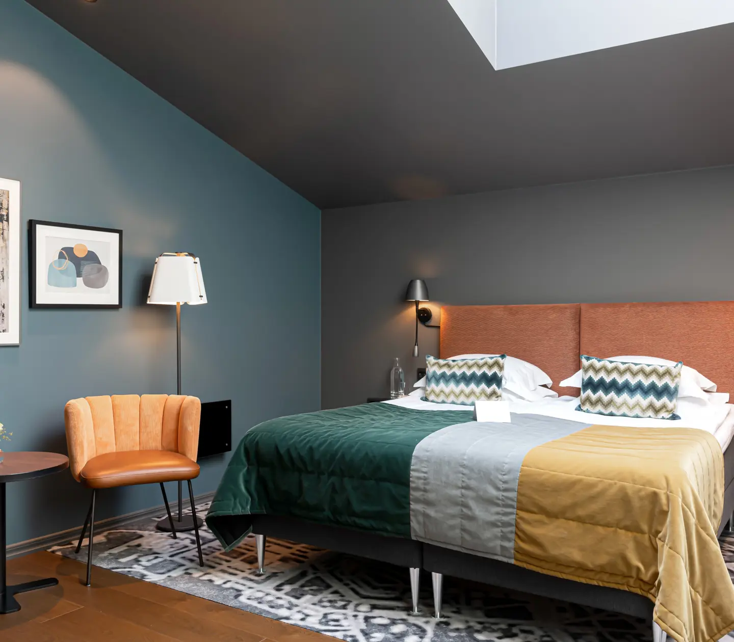 Colorful hotel room with double bed and armchairs
