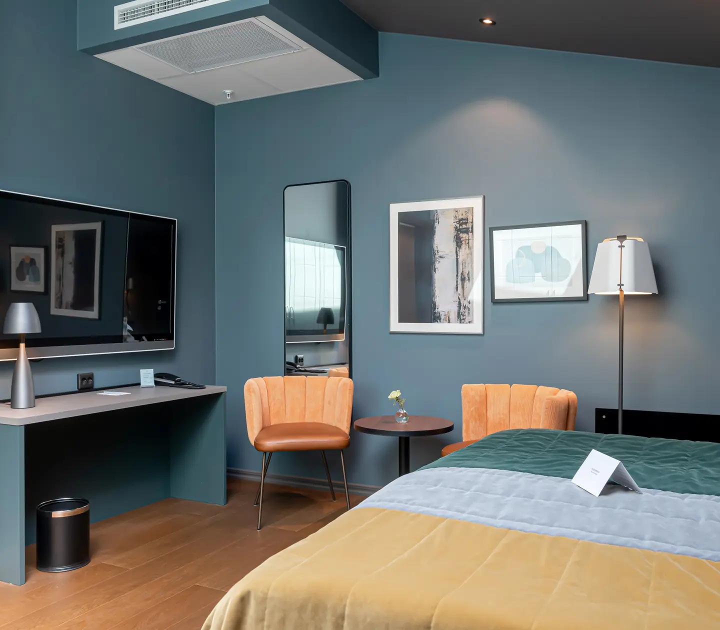 Colorful hotel room with double bed, armchairs and TV