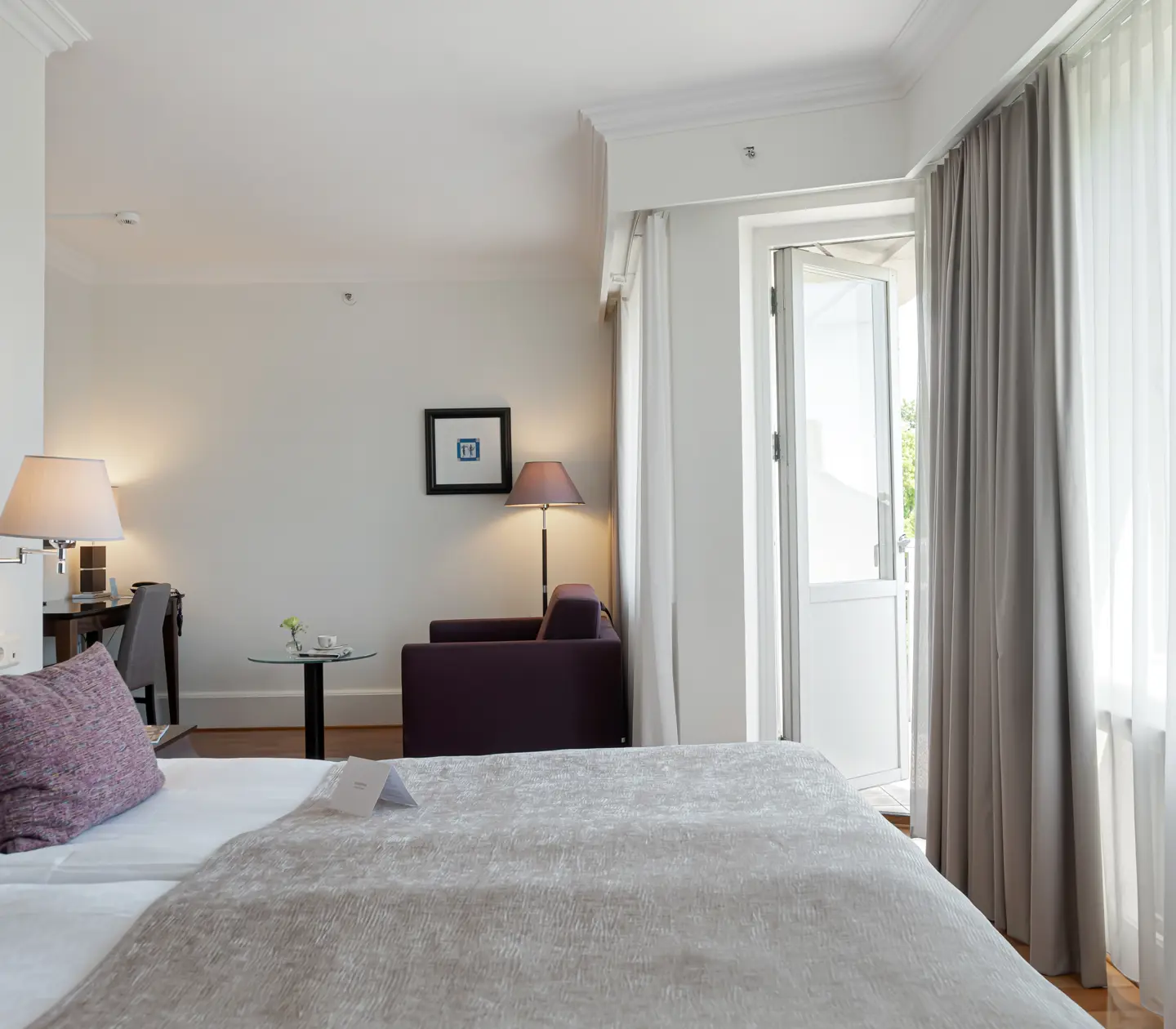 Cozy hotel room with double bed, armchair and balcony door