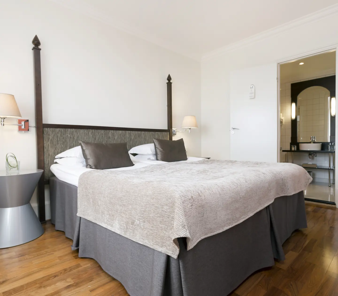 Hotel room with double bed, bedside lamps and door to bathroom